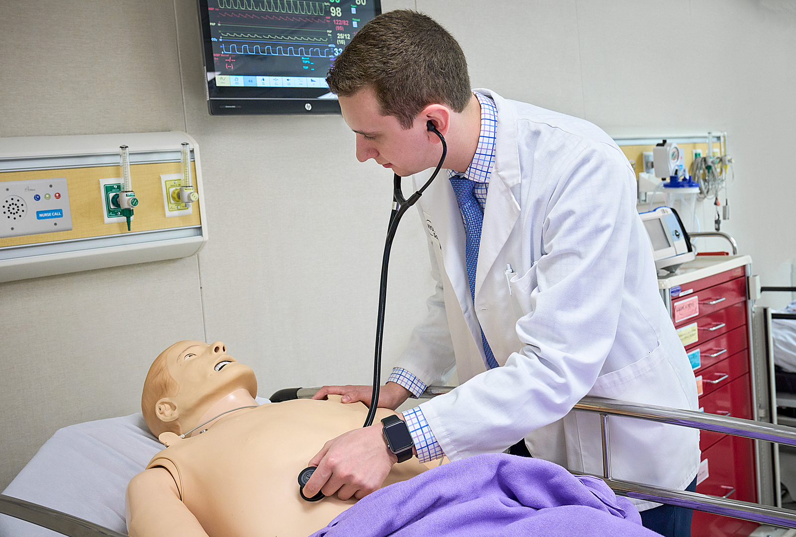 A medical student participates in patient simulation training using a medical manikin.