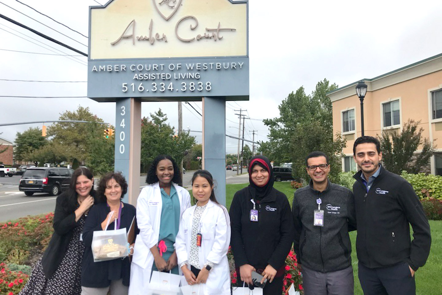 Office social worker and fellows posing outside of an assisted living facility in Westbury