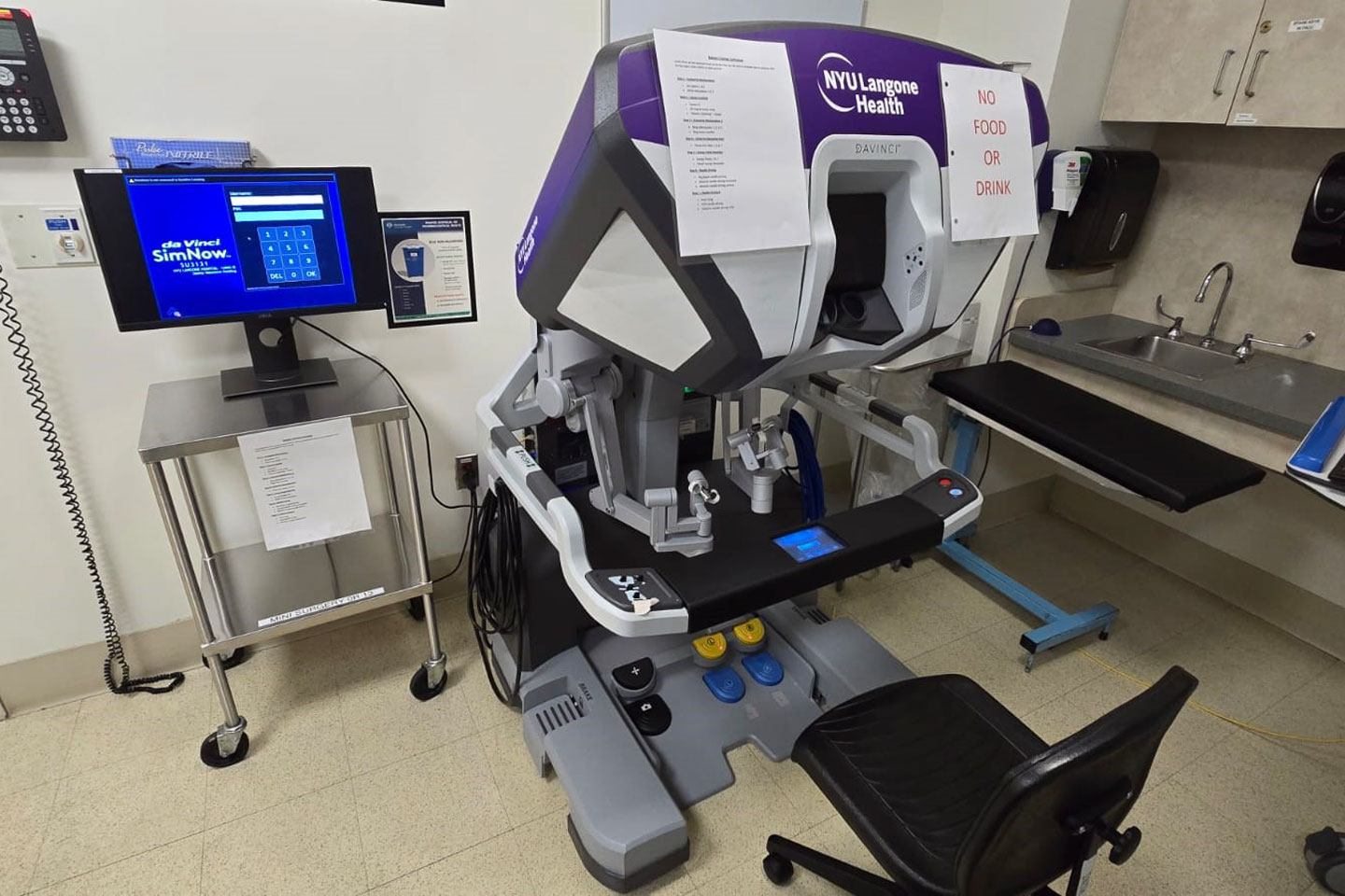 A robot simulation surgery trainer sitting next to a computer screen in a medical exam room.